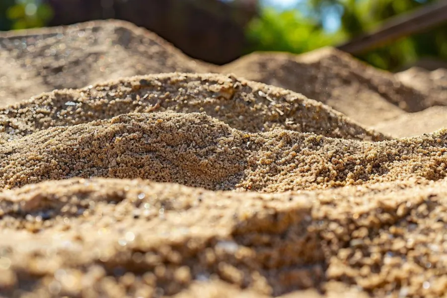 Close-up of coarse, gritty sharp sand grains in the sun
